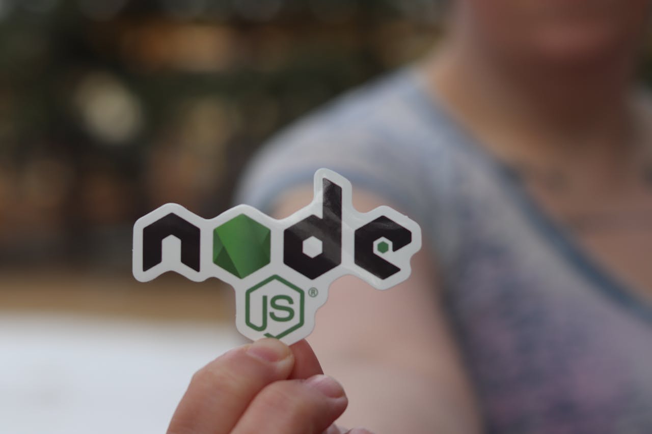 services-04 A person holding a Node.js sticker with a blurred background, close-up shot.